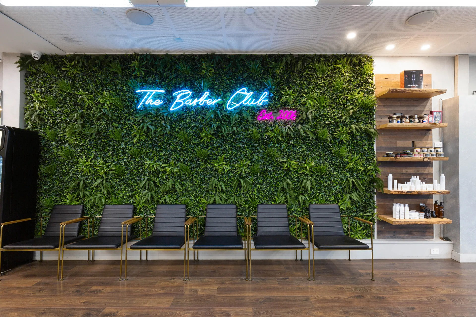 The signature green wall and Est. 2006 neon inside The Barber Club Bentleigh at 375 Centre Rd